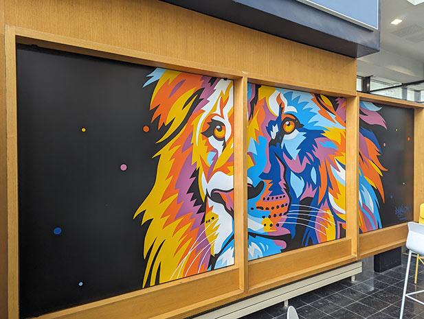 Oeuvre street-art représentant un Lion coloré sur trois panneaux.